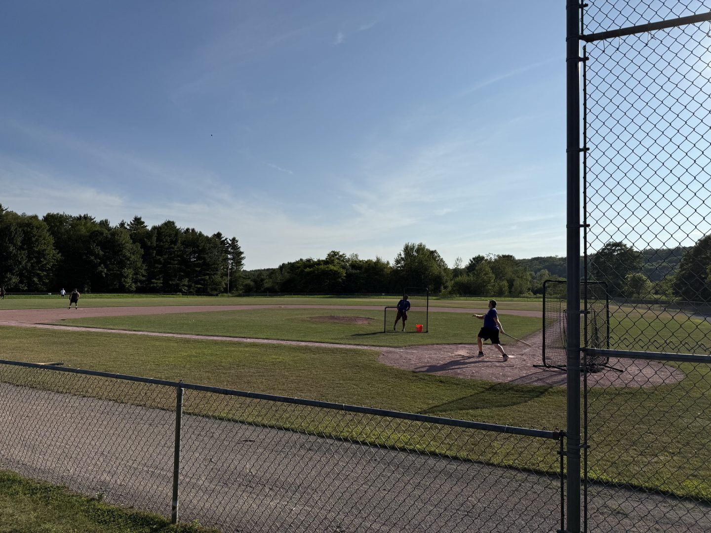 Baseball players practicing on the field during daytime.