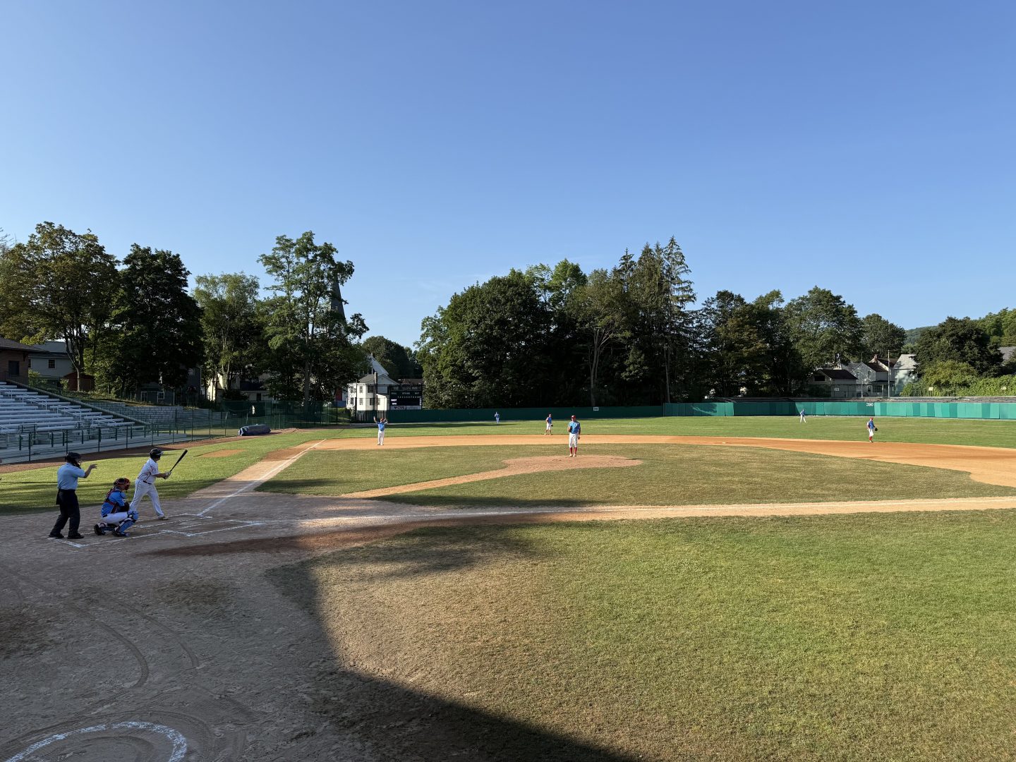 Youth baseball game on a sunny field with players and umpire.