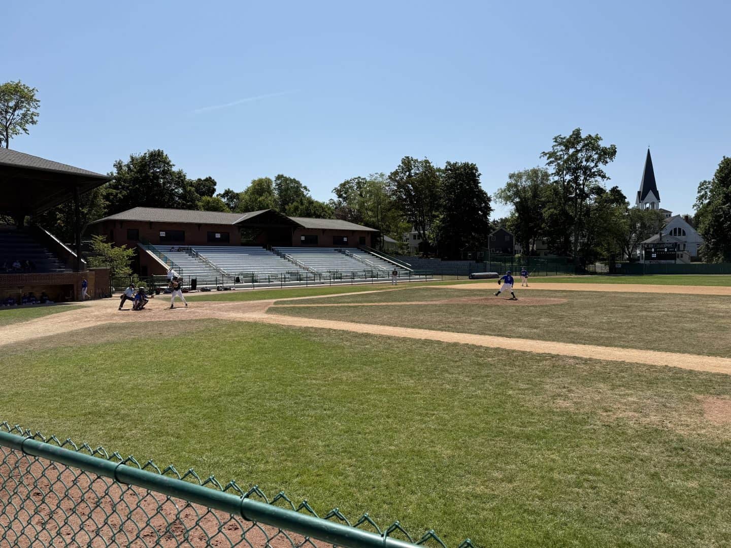 Baseball field with players practicing and a clear sky in the background.