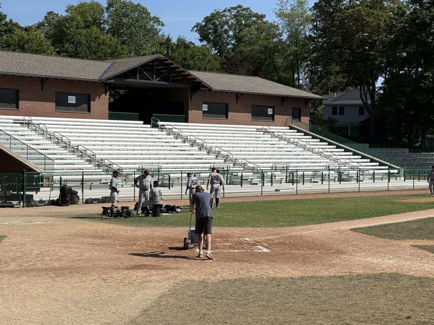 Players and coaches preparing for a game on a sunny day.