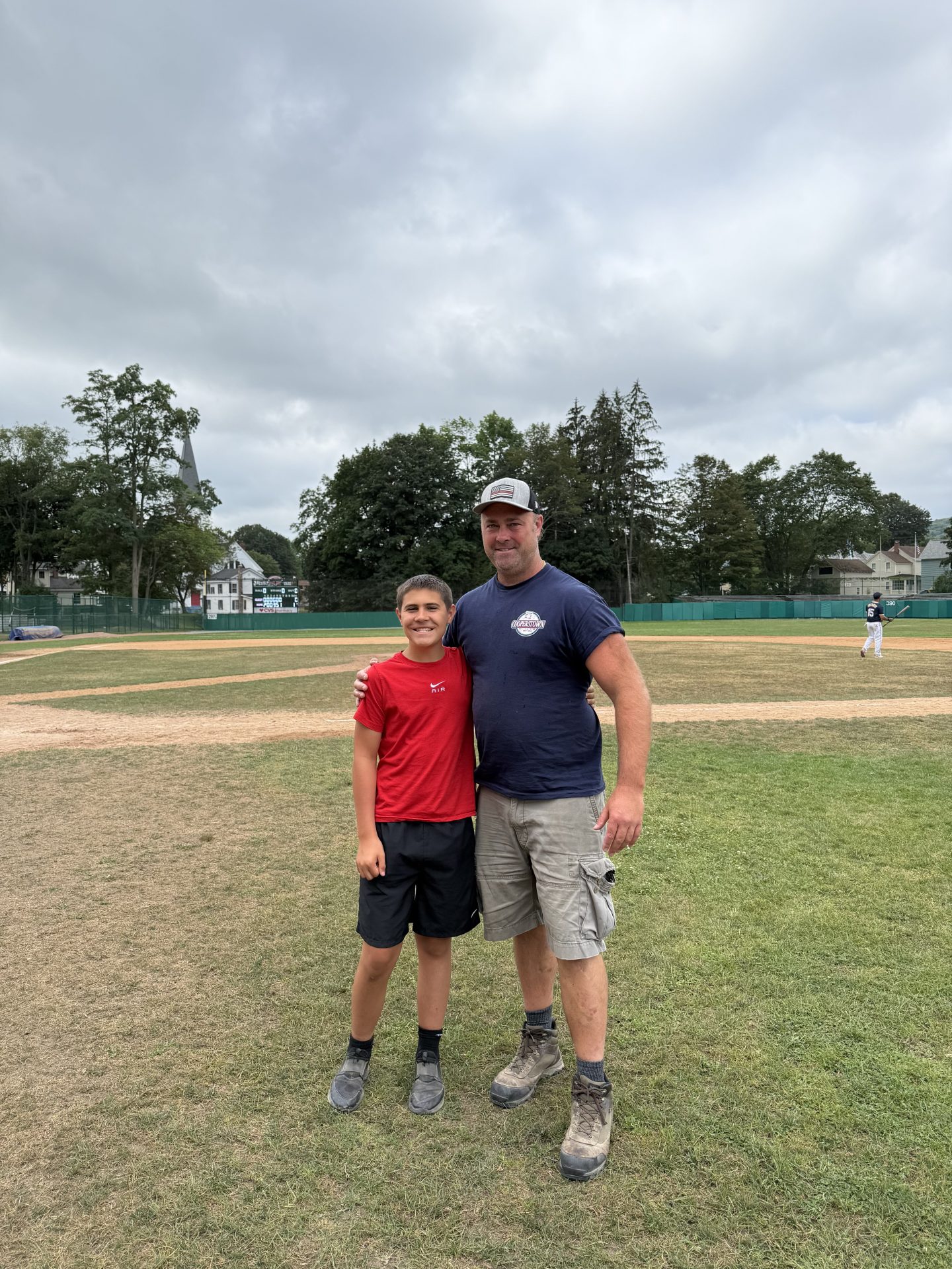 Baseball players on the field with coaches and spectators in the background.