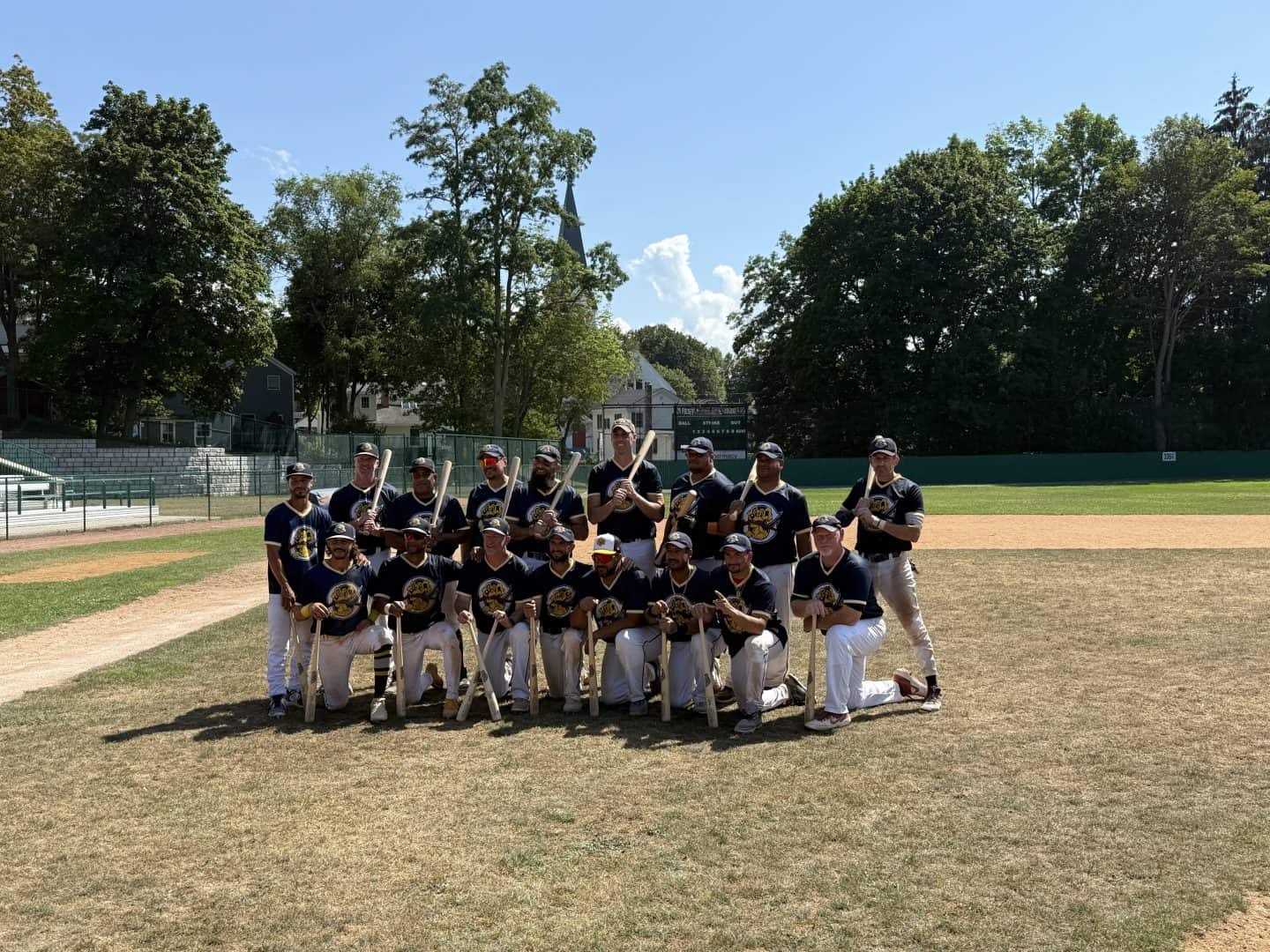 Baseball team posing on the field during daytime game.